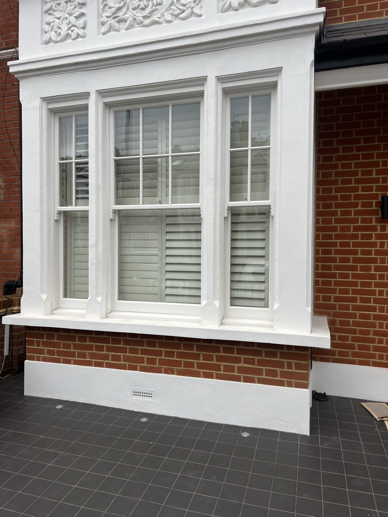 Restored bay window with new timber box sashes and repaired decorative panels